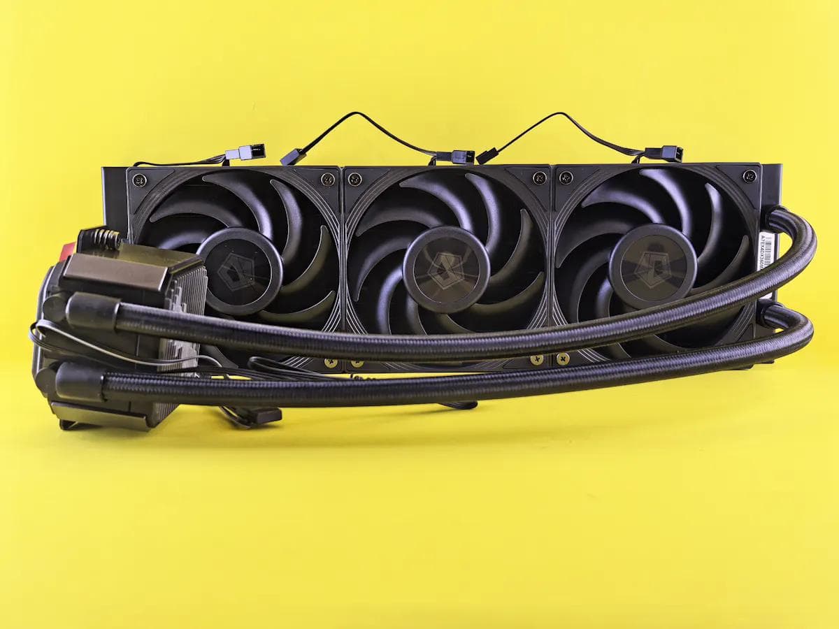 Computer liquid cooler with three black fans against a yellow background.