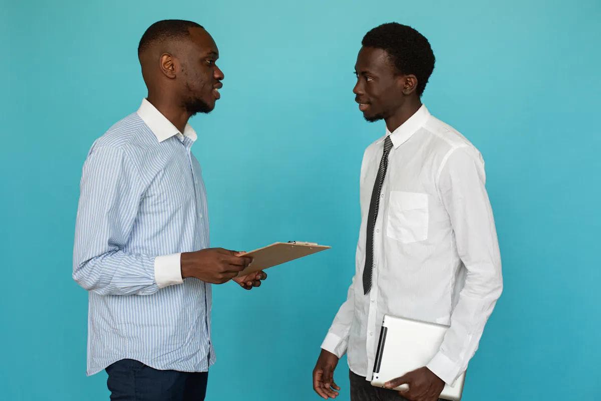 Two Black businessmen discussing business efficiency, one holding a tablet.