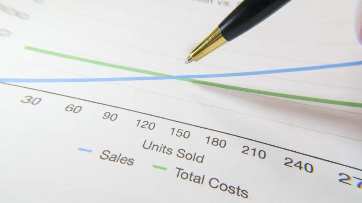 Sales vs costs chart showing business efficiency metrics with a pen pointing.