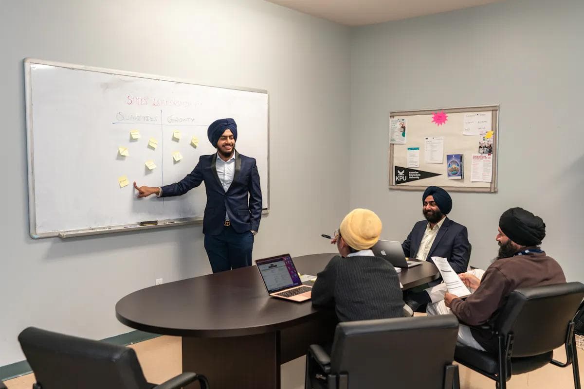 Business meeting with diverse professionals discussing strategy on a whiteboard.