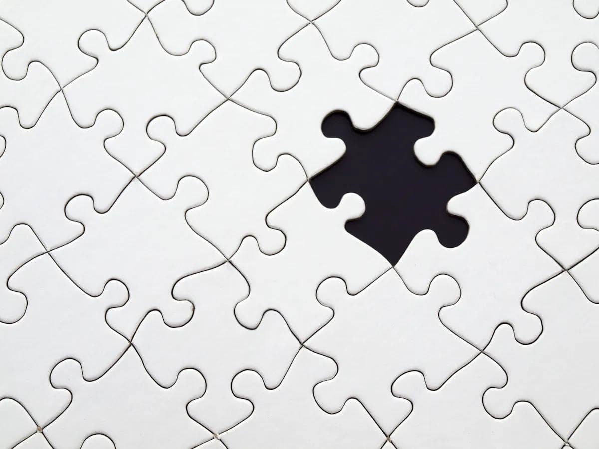 White jigsaw puzzle with one piece missing, showing dark background.